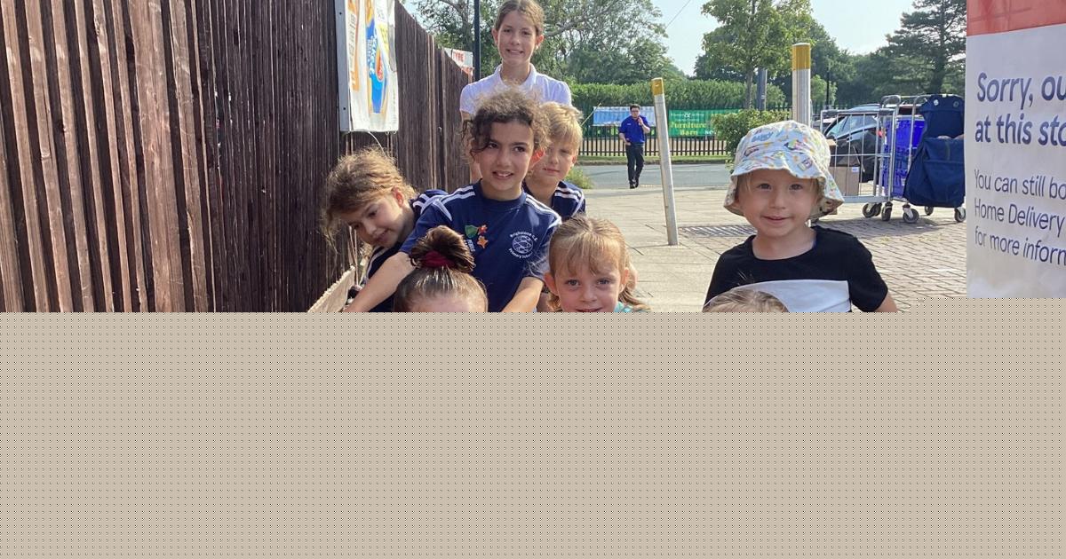 Children help colourful stone 'snake' slither around supermarket car park