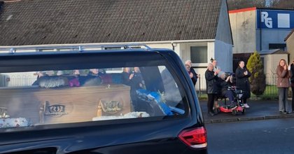 Crowds line the street to pay respects to beloved shop owner