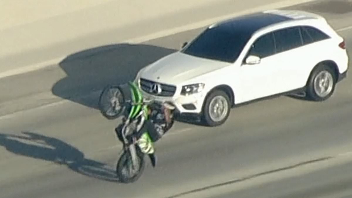 Dystopian Mad Max scene on LA freeway as car thief in stolen SUV is surrounded by huge gang of illegal dirt bikers