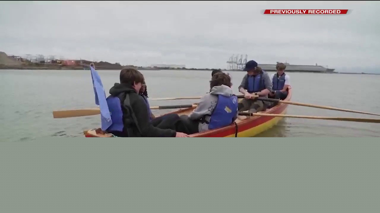 Students launch boat into the bay, they built themselves