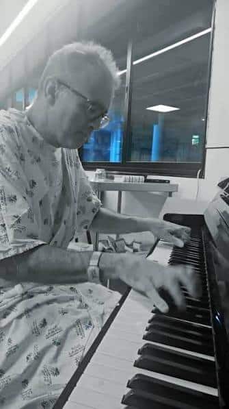 A pianist plays in a hospital gown